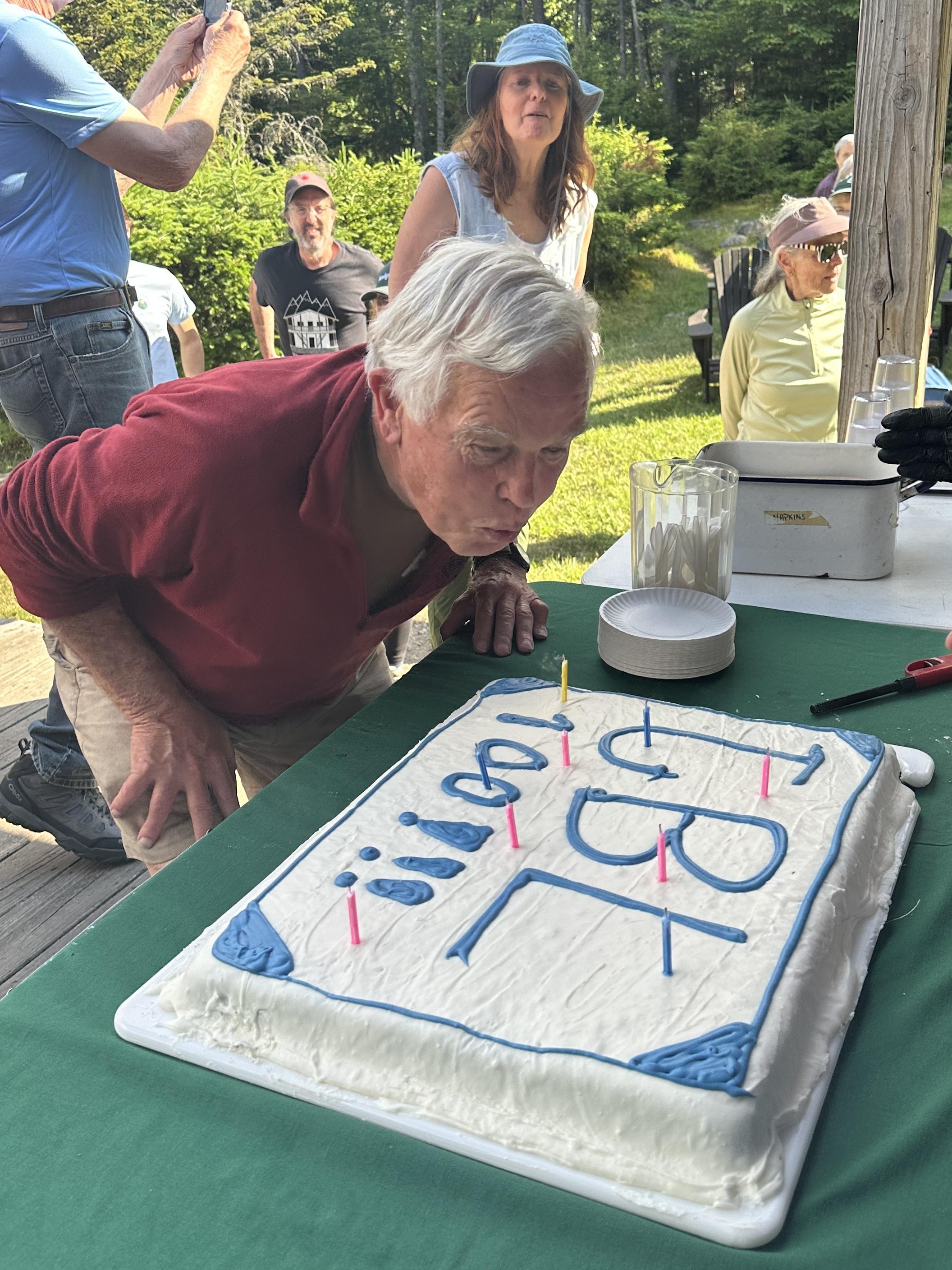 a man blows out candles on a cake outdoors
