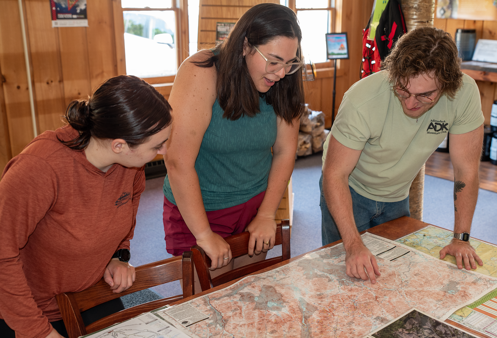 three people looking at a map unfolded on a table