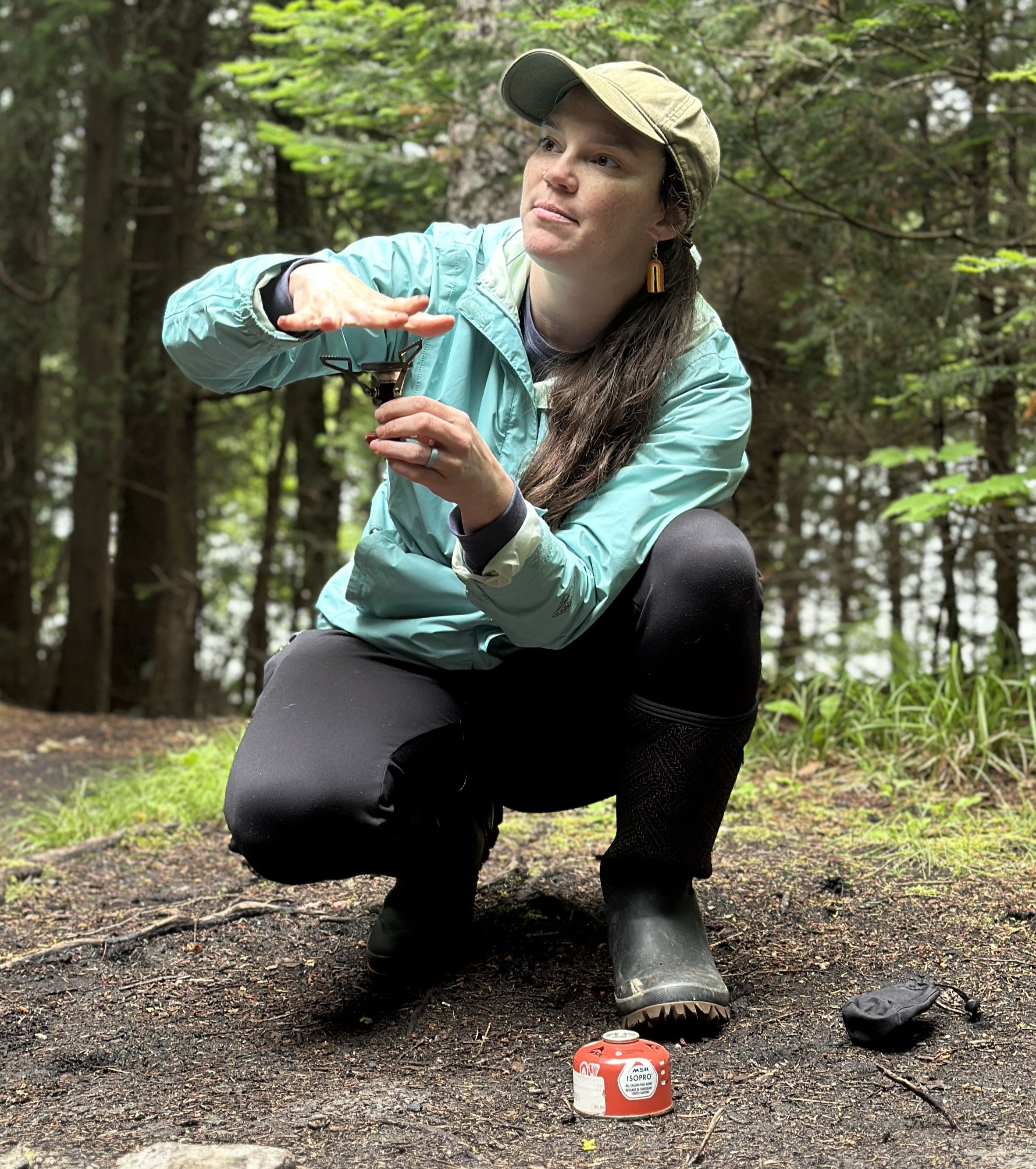 woman in a blue coat demonstrates how to use a portable stove