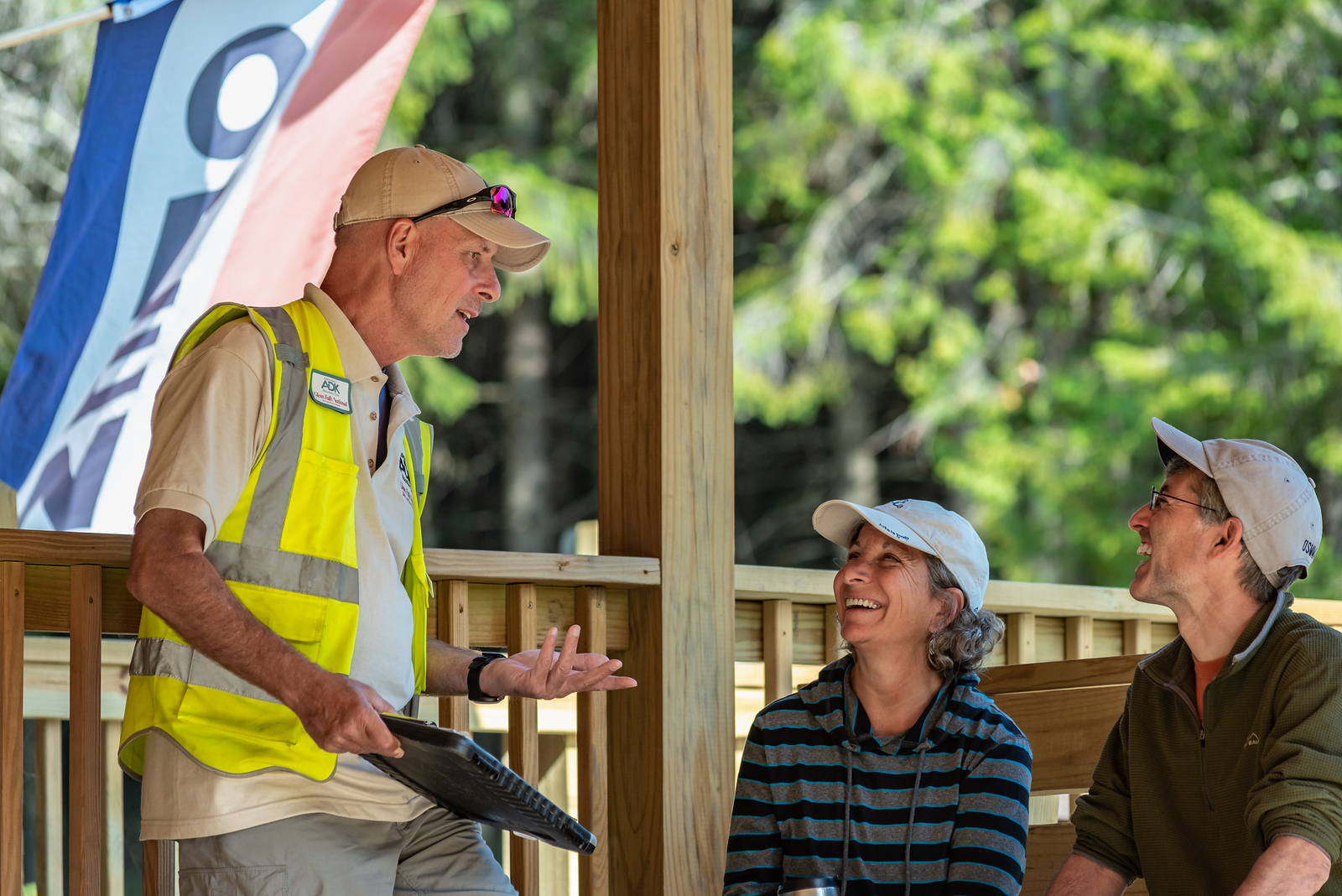 male ADK volunteer trailhead steward speaks to two hikers at High Peaks Information Center